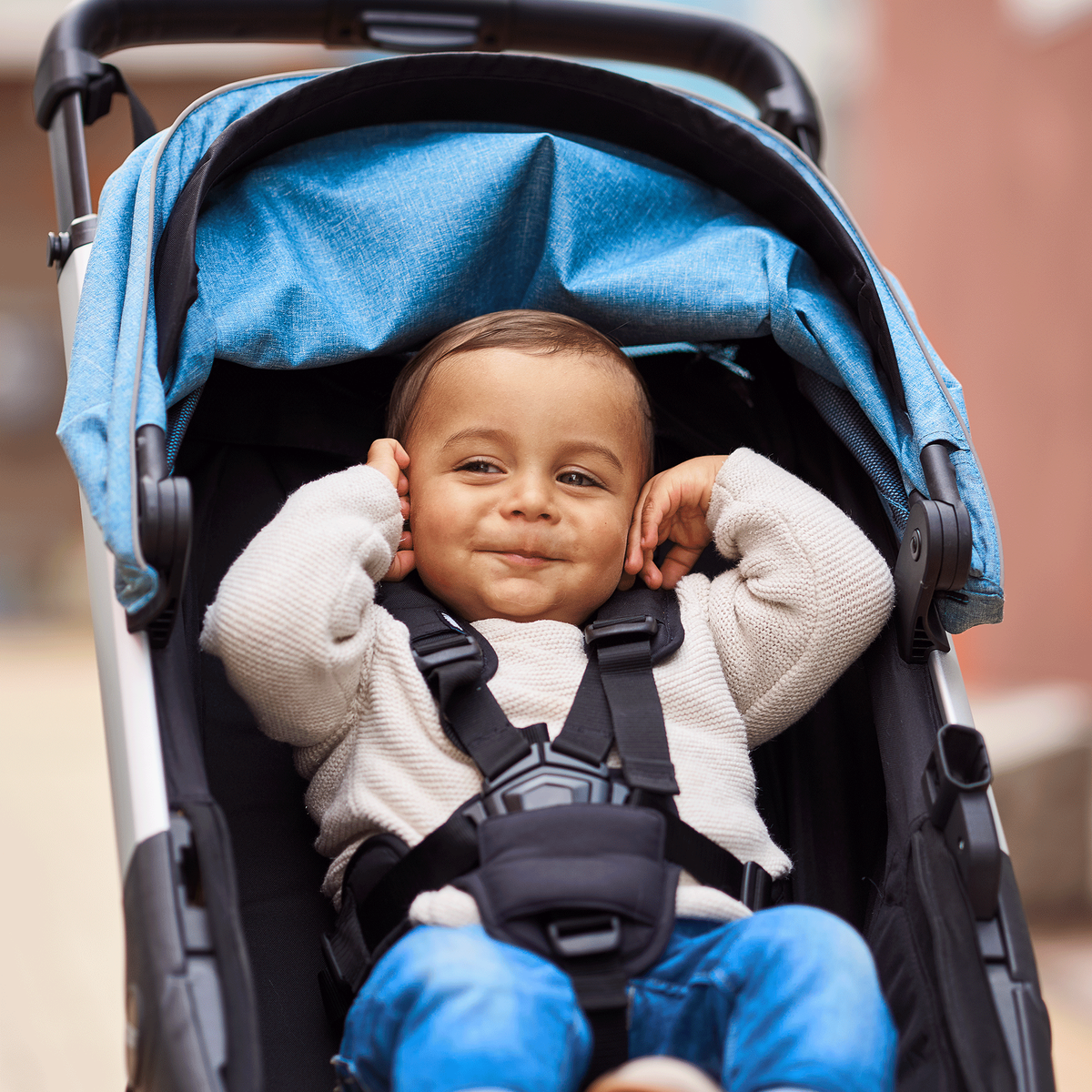 A close-up of a toddler smiling in a blue Thule Spring compact stroller.