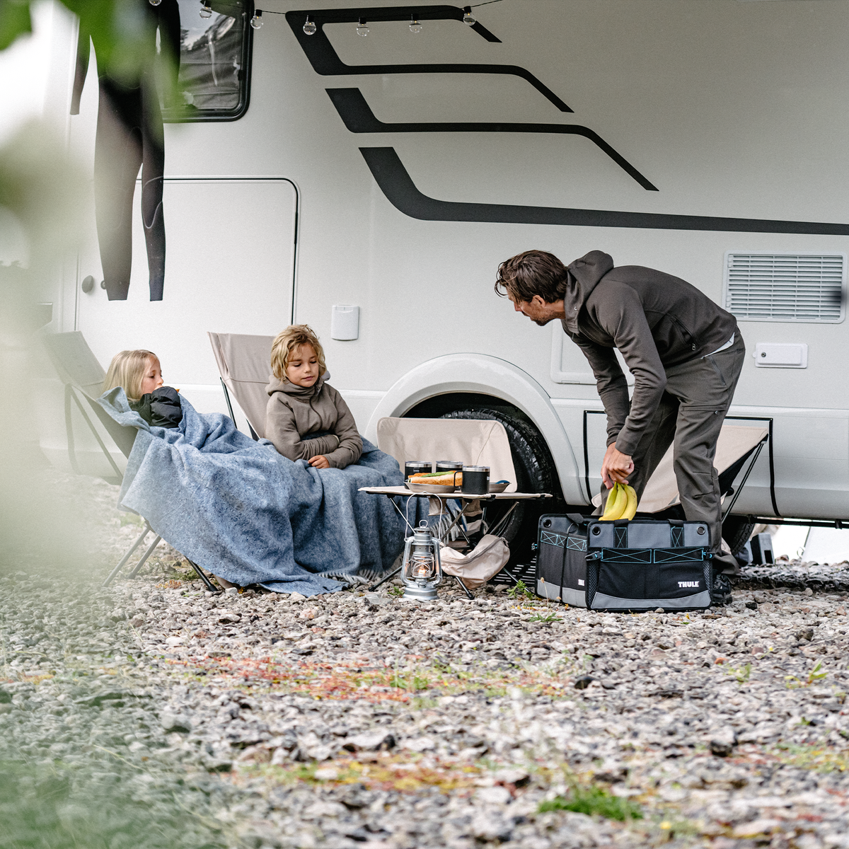 Outside of a motorhome, a person loads things into a Thule Go Box rv organizer.