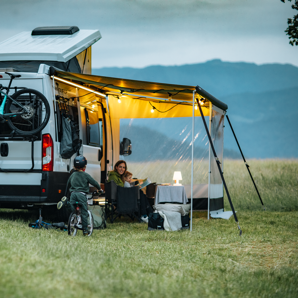 A man walks towards a motorhome with a pop-up roof and a Thule Omnistor 5200 motorhome awning.