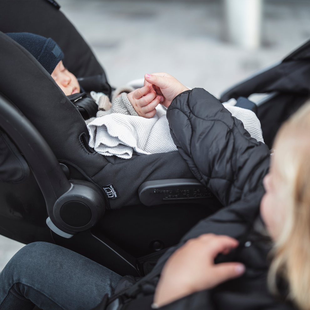 A close-up of a baby sleeping in a car seat thanks to the Thule Urban Glide 2 Car Seat Adapter.