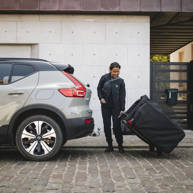 A woman is mounting a Thule Outset tent on her car.