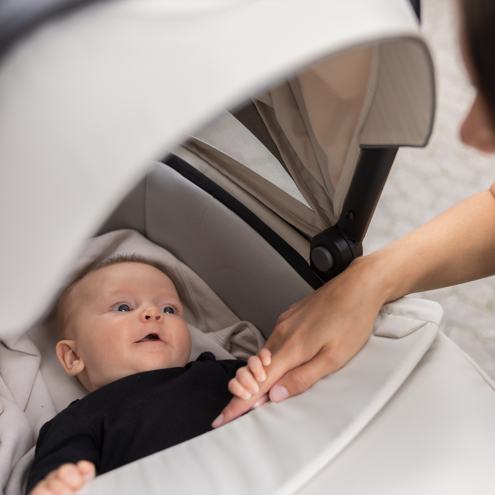 A close-up of a baby inside of a cream-colored Thule Urban Glide 3 all-terrain stroller.