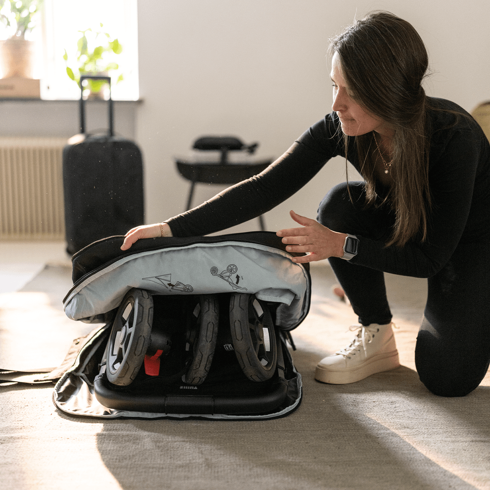 A woman unzips her Thule Stroller Travel Bag to pack up her Thule stroller.