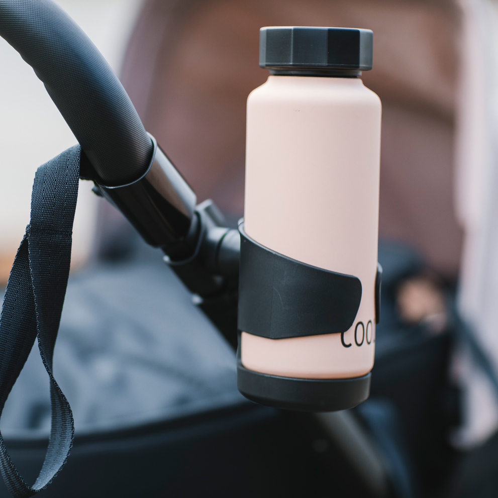 A close-up of a pink thermos placed inside the Thule Stroller Cup Holder.