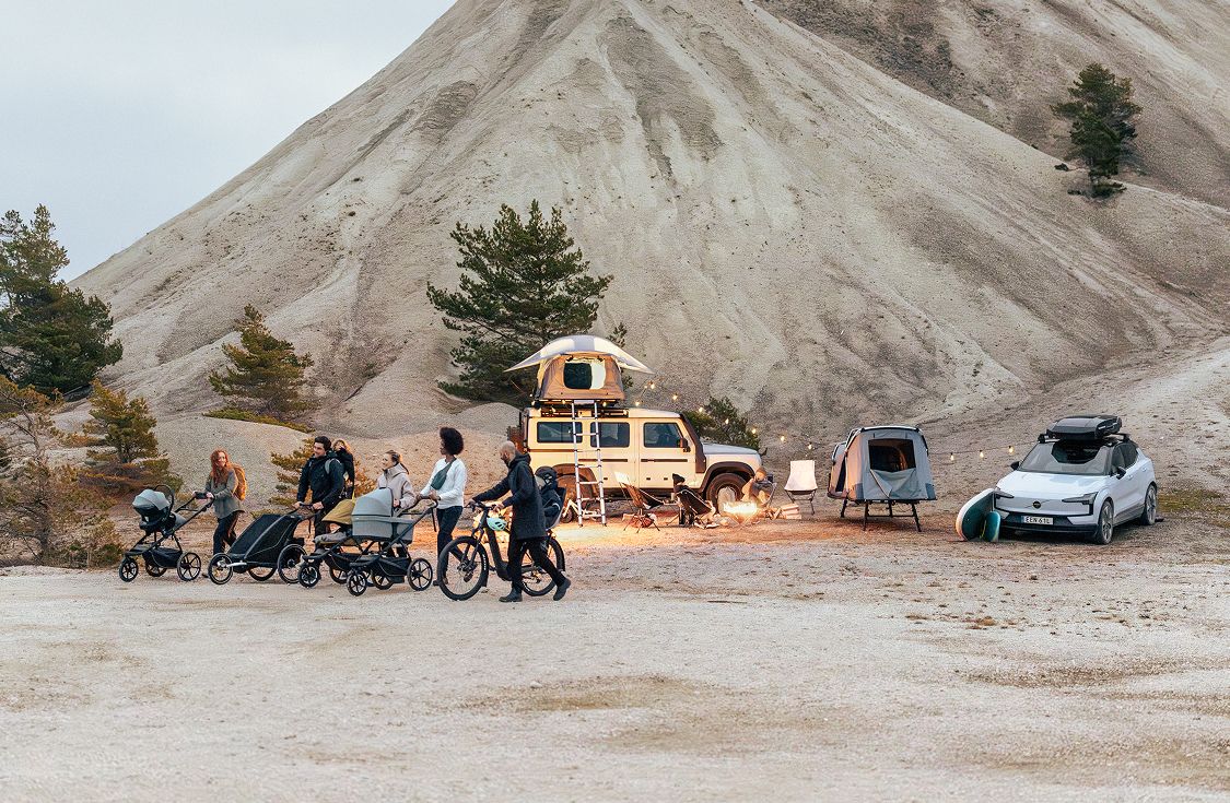 A group of people with different kind of gear from Thule walking together beside a camping spot.