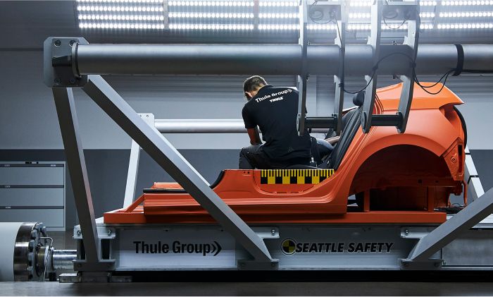 A woman is preparing a crash test of a Thule car seat in the Thule Test Center.