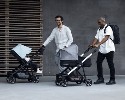 Two dads walks with their kids in a Thule Shine lightweight stroller.