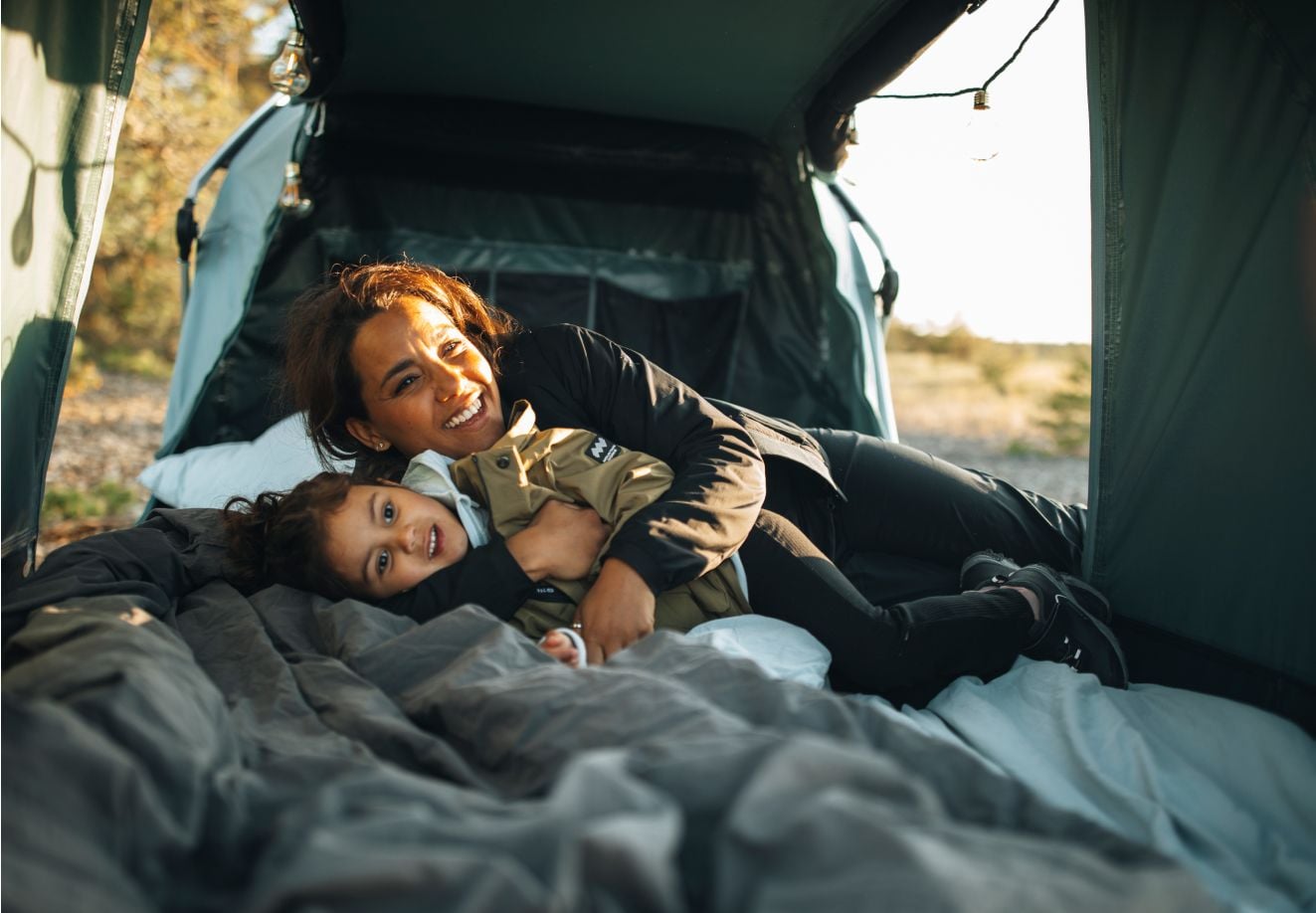 Voksen og barn leker sammen i et Thule Outset-biltelt.