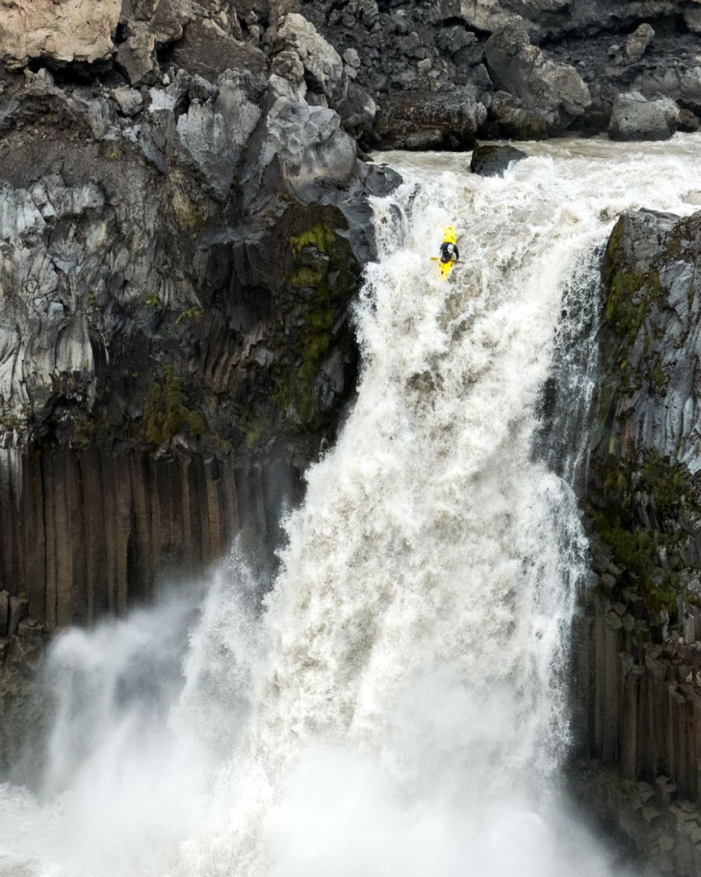 A person in a kayak goes over the edge and starts to descend on a large waterfall.