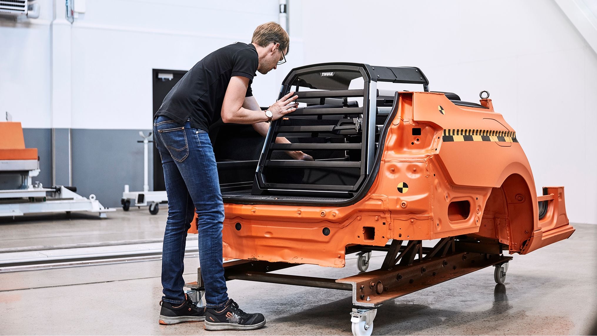 Person testing a Thule Allax dog crate installed in a vehicle body during a crash safety test.