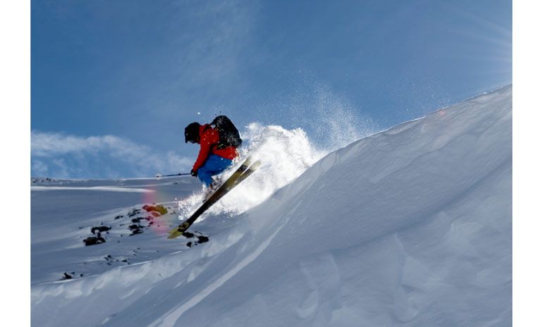 A skier skis down the slopes in full speed with a Thule Upslope on a sunny day.