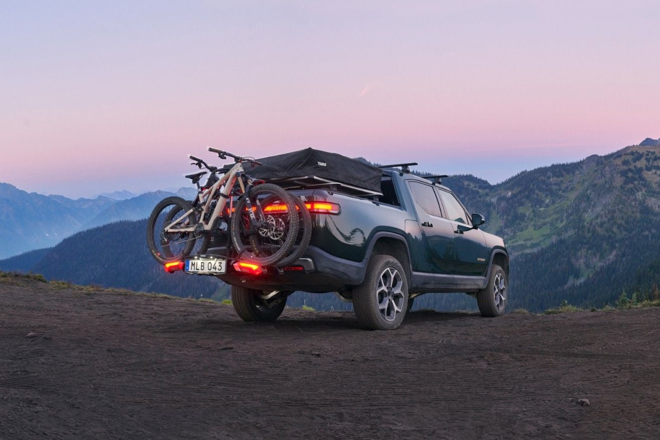 Un camion pick-up est stationné dans les montagnes avec un support à vélos avec un baron de remorquage et des vélos attachés,