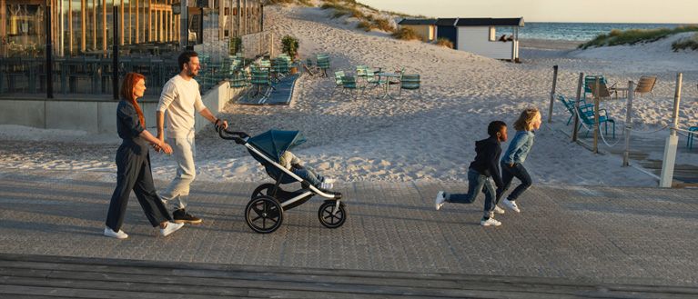 Family walking on the boardwalk with stroller Thule Urban Glide 2 blue