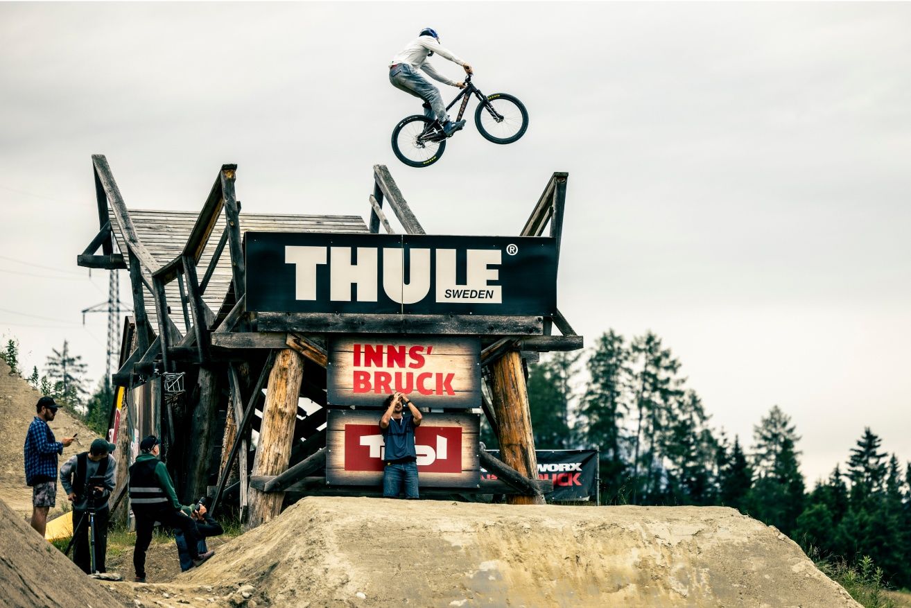 Un participant réalisant une figure en l'air sur la scène de Slopestyle Thule de VTT au festival Crankworx d'Innsbruck. 