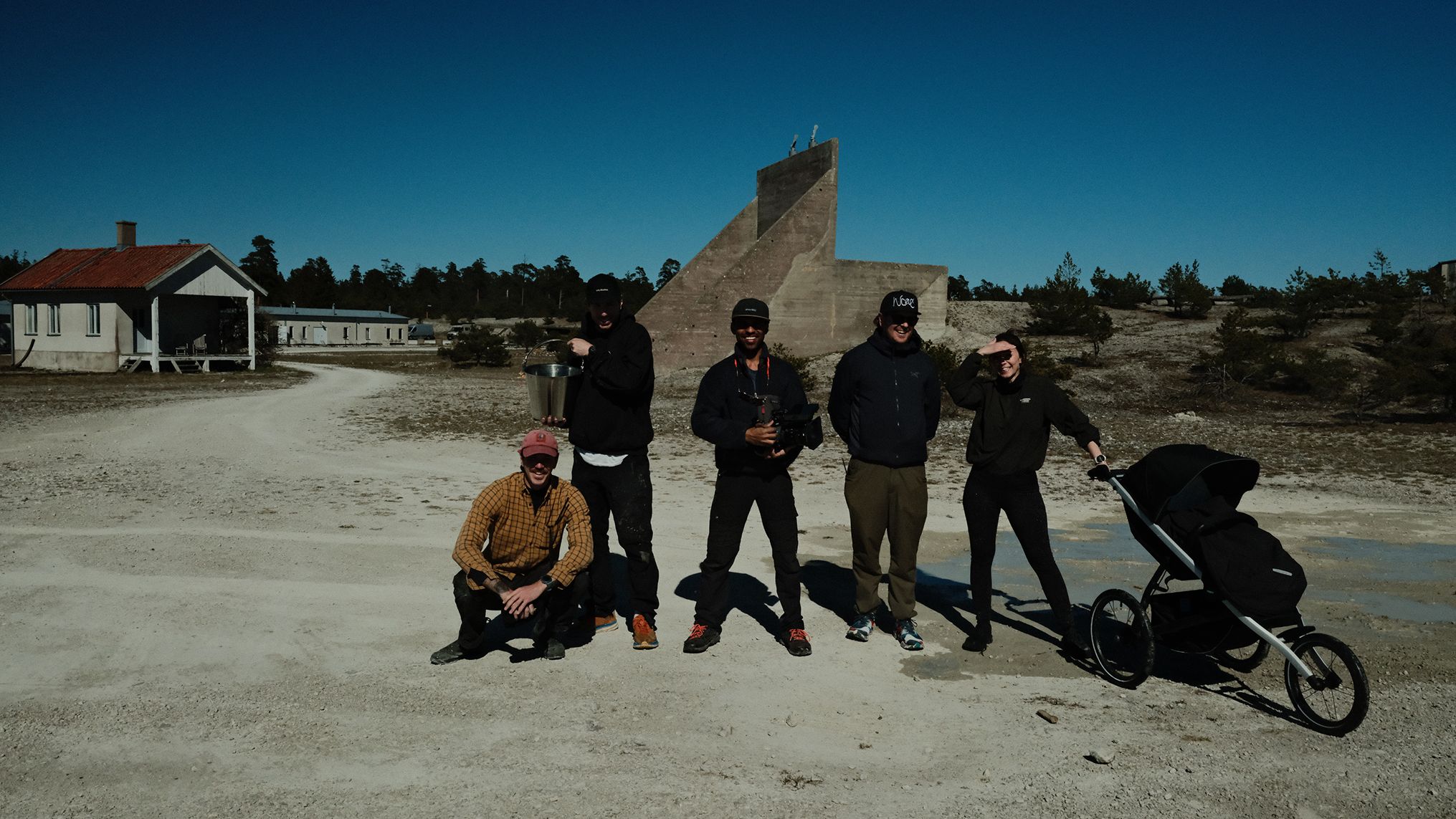 Nos bastidores da campanha A Different Kind of Strong da Thule, com cinco membros da equipe posando juntos ao lado de um Thule Urban Glide 3 em uma paisagem rochosa.