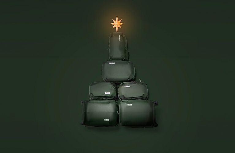 Four green Thule Chasm duffel bags are piled high with a star on the top like a Christmas tree.