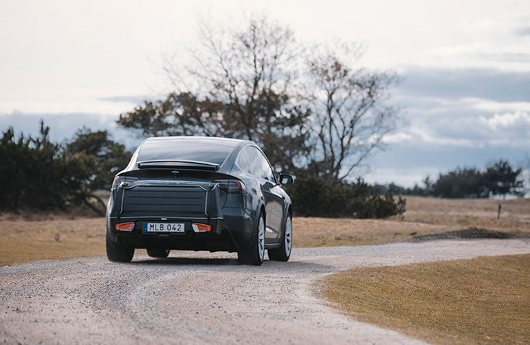 一辆载有 Thule Onto 拖车箱的汽车在街道上行驶。