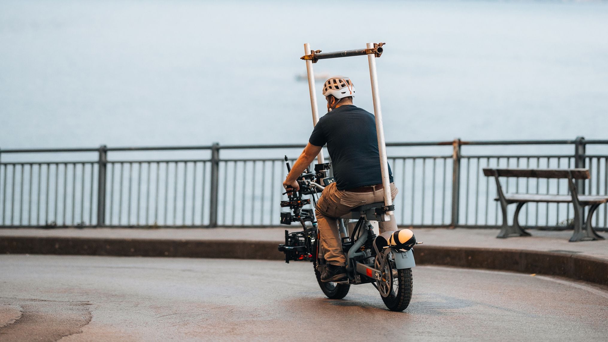 En filmskaper kjører en elektrisk motorsykkel modifisert for å bære et profesjonelt filmkamera og navigerer i gatene for å fange dynamiske bilder.