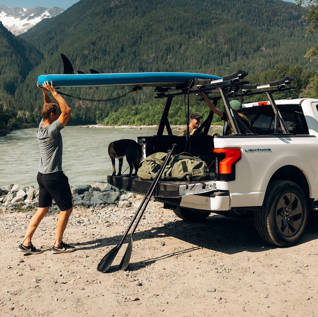 Person loading gear onto a pickup truck with a Thule Xscape truck rack.