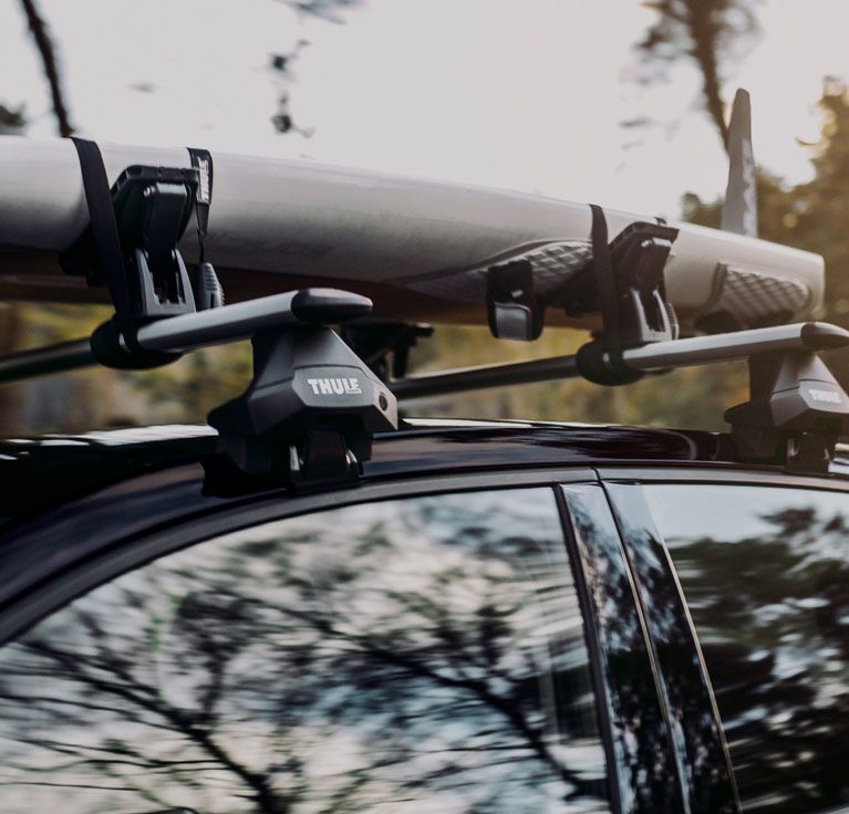A close up of a black Thule roof rack with a SUP rack attached