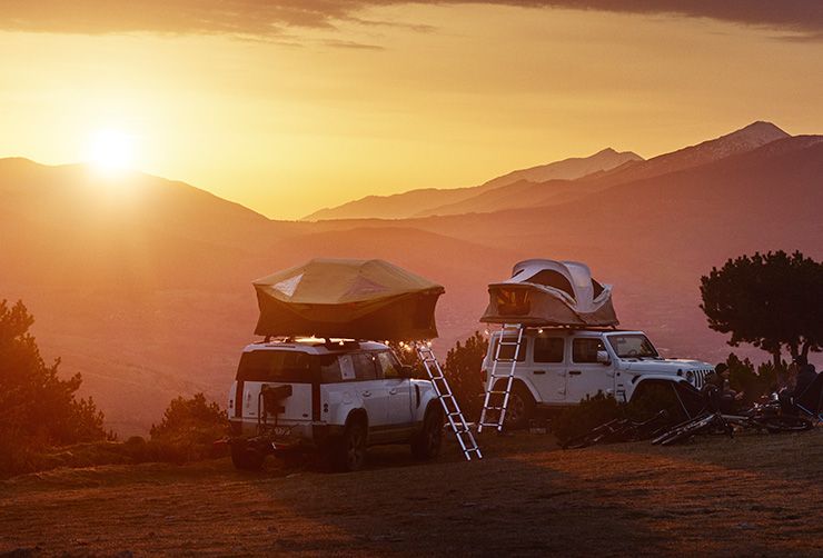 Two jeeps with Thule Approach roof top tents in the mountains with a setting sun.