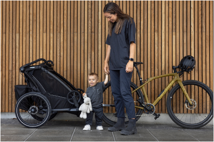 Kvinde og barn står ved siden af en cykel med en cykeltrailer.