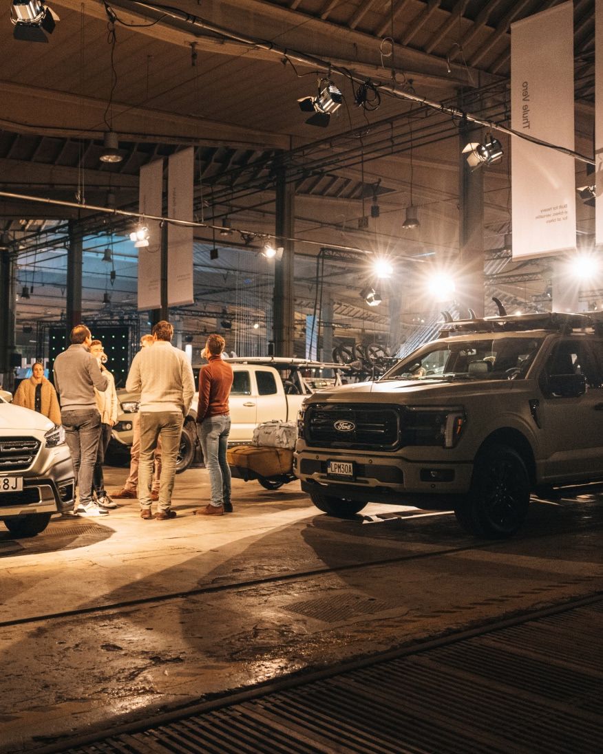People walking among displayed vehicles at an indoor event.