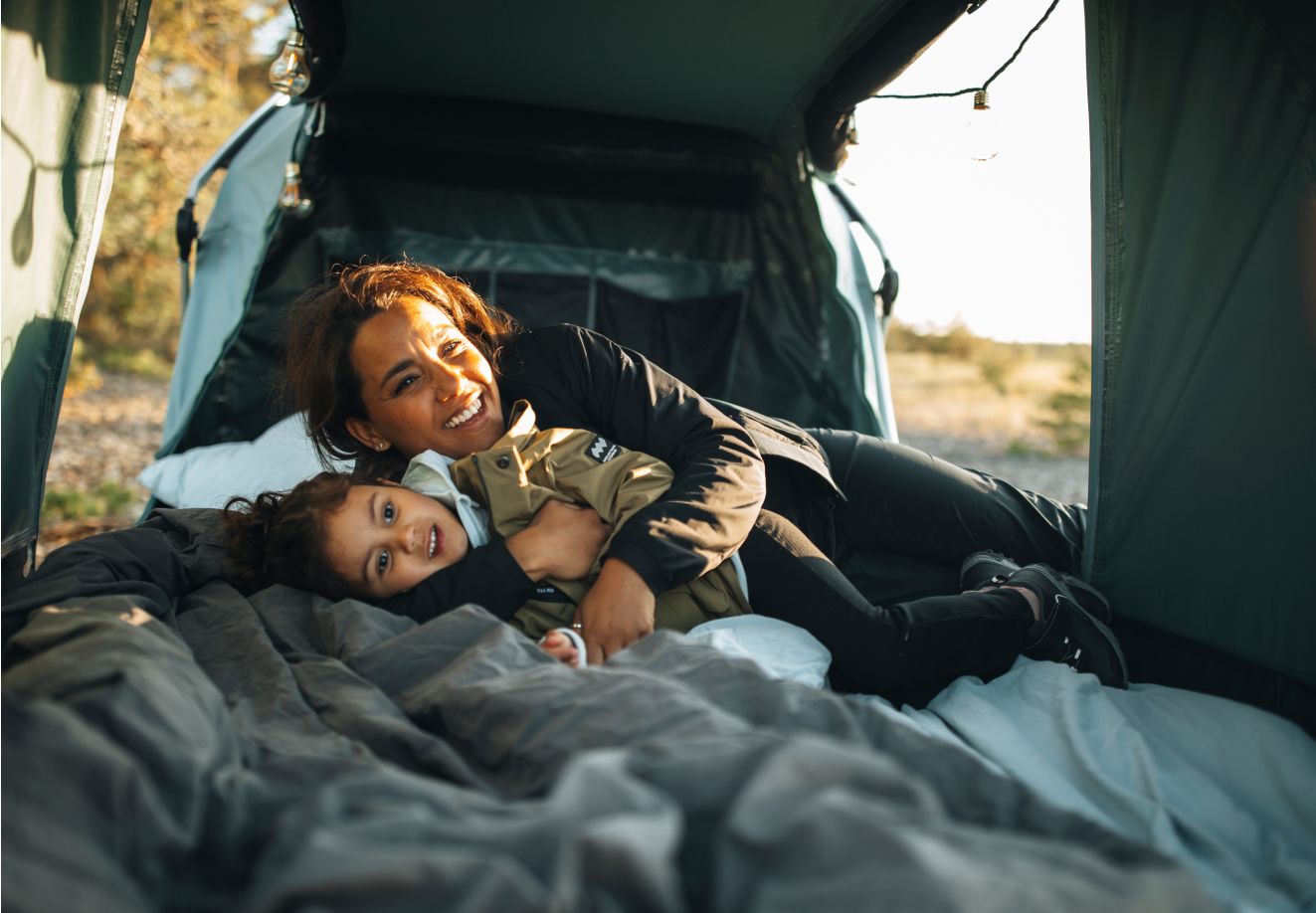 Взрослый и ребёнок играют вместе в автомобильной палатке Thule Outset.