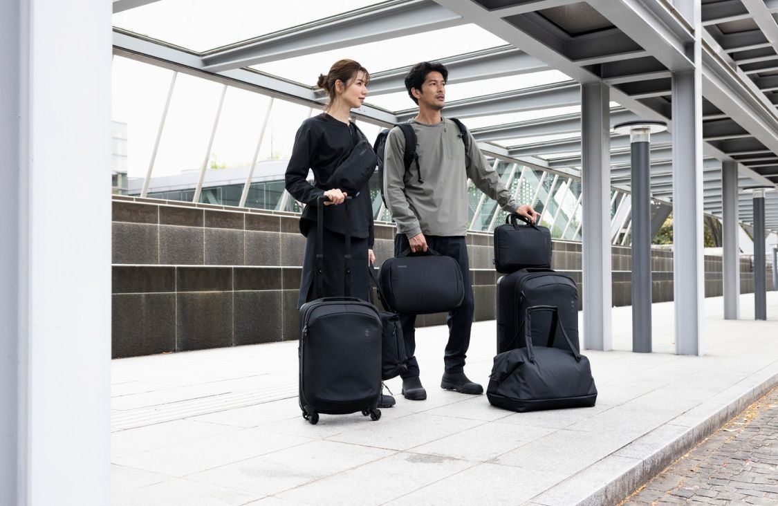 A man and woman stand on a train platform holding the Thule Subterra luggage collection.