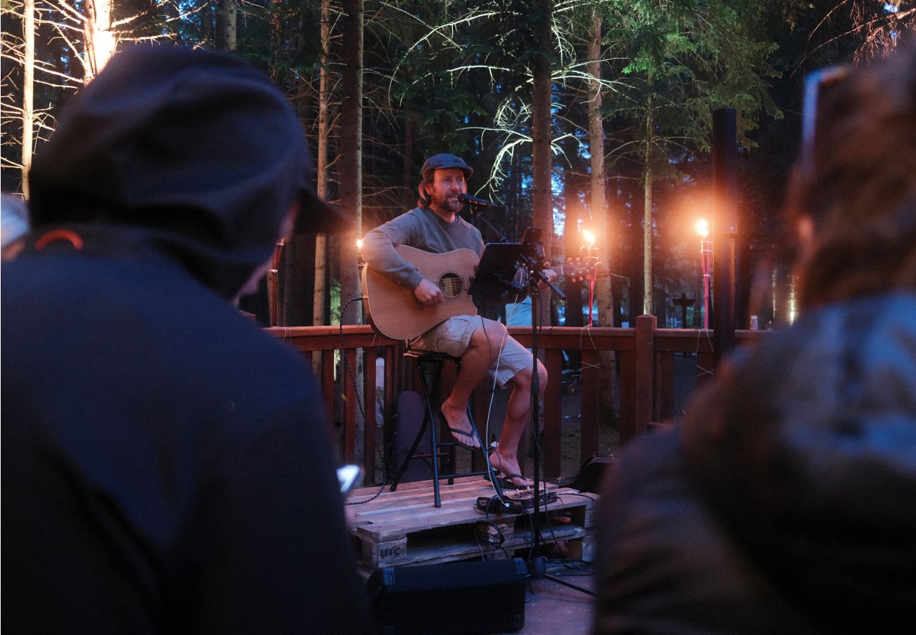 Uma pessoa toca guitarra e canta no palco do encontro Adventure Life by Thule em Innsbruck.