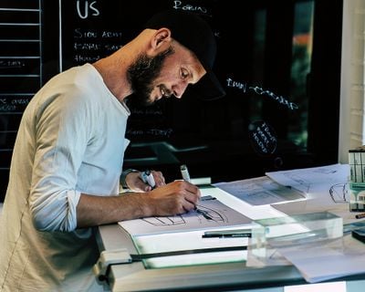 자신의 책상에서 뭔가를 그리고 있는 Thule 디자인 책임자의 사진.