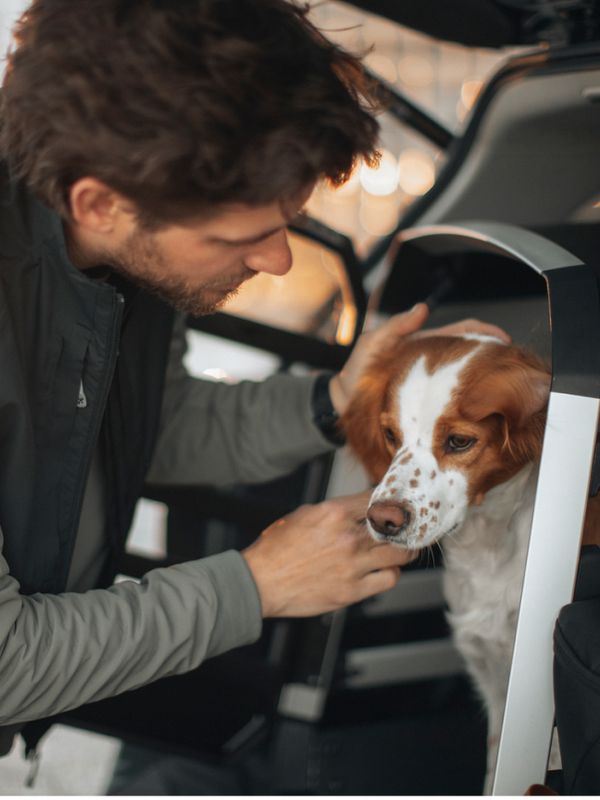 En man står bredvid sin hund, säkert placerad i en Thule Allax hundbur