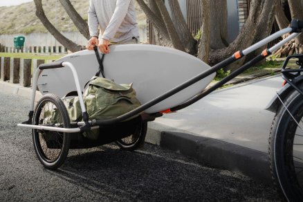 Trailer de carga para bicicletas carregado com equipamento estacionado perto de uma calçada.