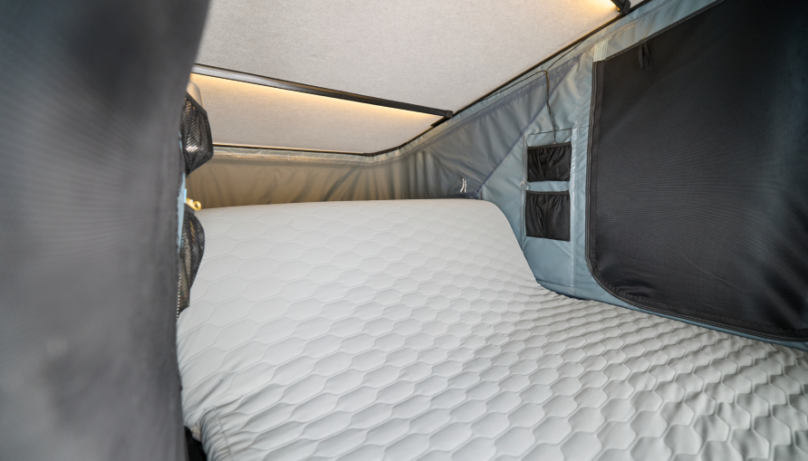 Matelas douillet, canapé et éclairage dans une tente dépliée sur le toit