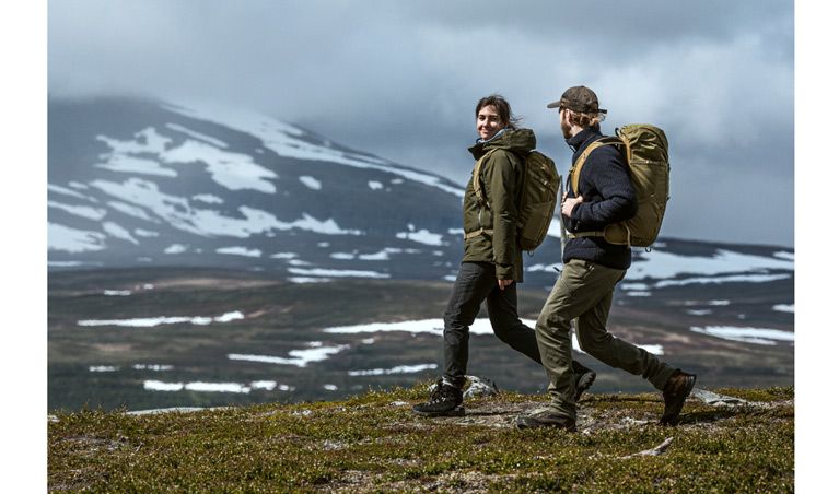 Two people walk in the mountains with the hiking backpack Thule Alltrail X.