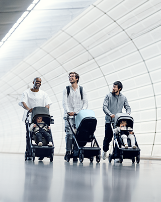 Kolme isää kävelee metroaseman läpi kompaktikokoisten kaupunkikäyttöön tarkoitettujen Thule Shine ‑lastenrattaiden kanssa.