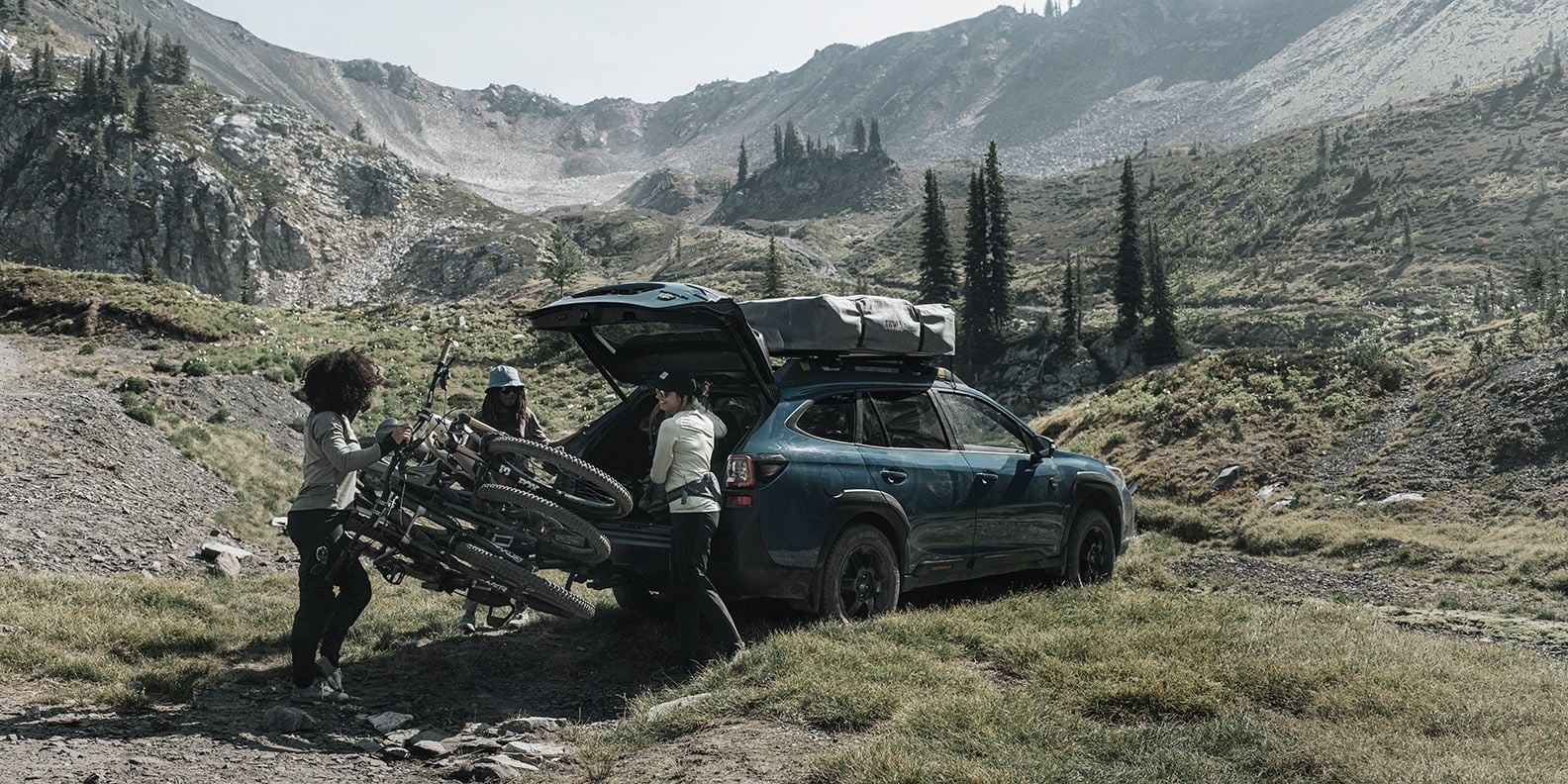 En kvinna viker undan Thule Epos cykelhållare lastad med tre cyklar för att komma åt bagageutrymmet