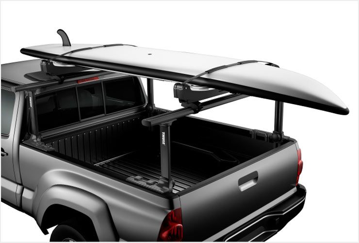 A close up of a truck with a Thule Xsporter Pro pickup truck rack and a SUP board attached