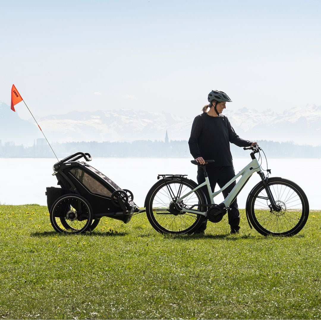 Parent cycling with a child trailer in an nature setting.