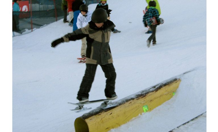 A boy shows off his snowskating skills at a competition.