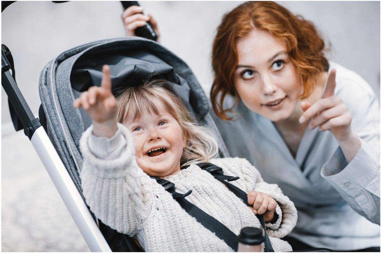 A mother points up to the sky together with her child who sits in a Thule stroller.