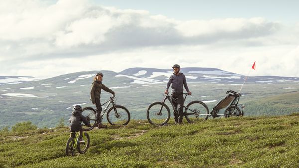 A family rides on bikes with a Thule Chariot bike trailer in the countryside.