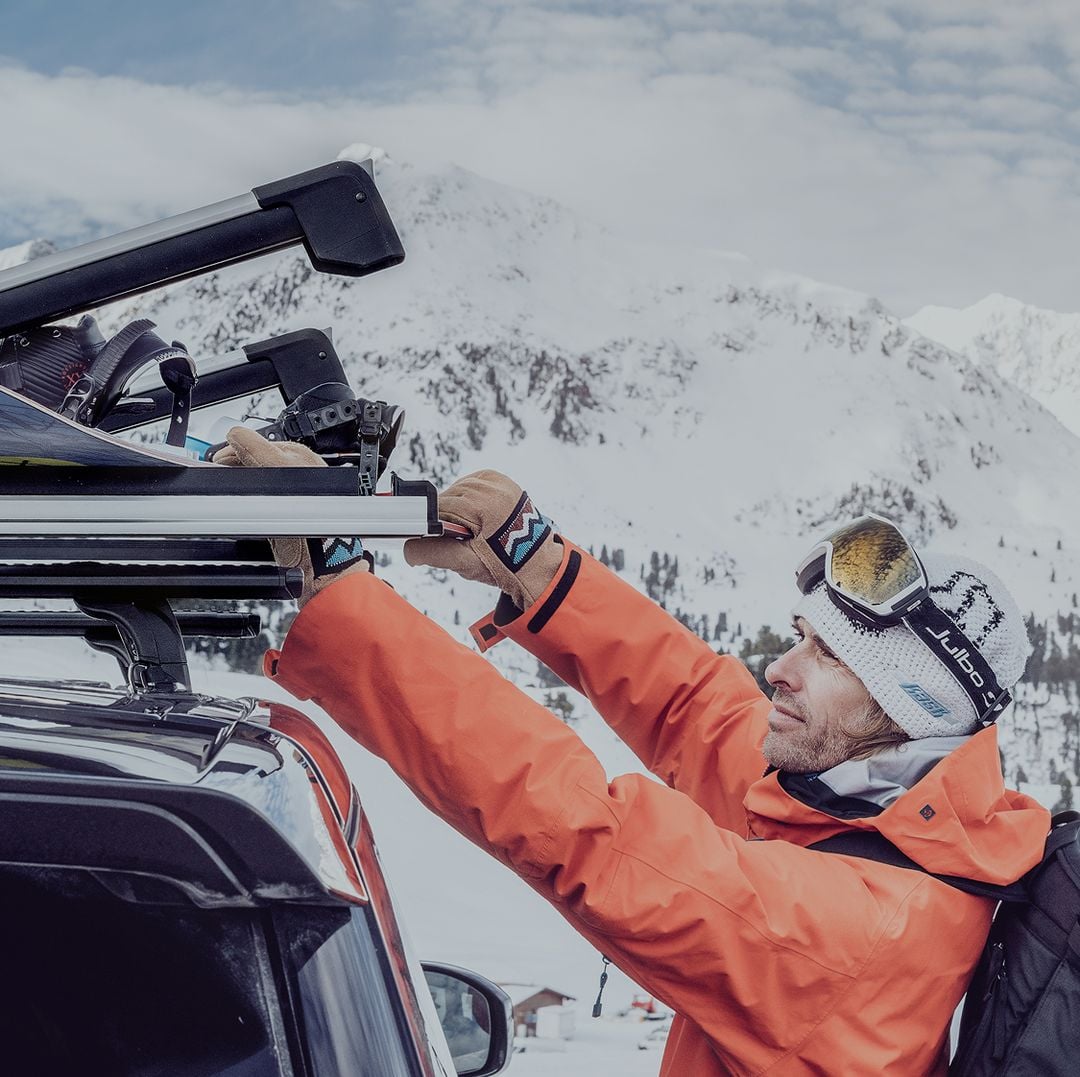 Thule Outlet hero banner showing a skier loading gear onto a roof rack in a snowy mountain landscape.