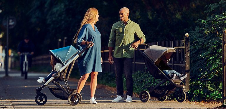 A man and a woman talking, with one Thule Spring city stroller each. 