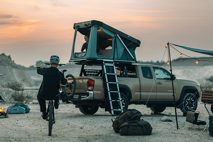 Hardshell-tent op kamperen. Een vrouw in de tent en een man op een fiets