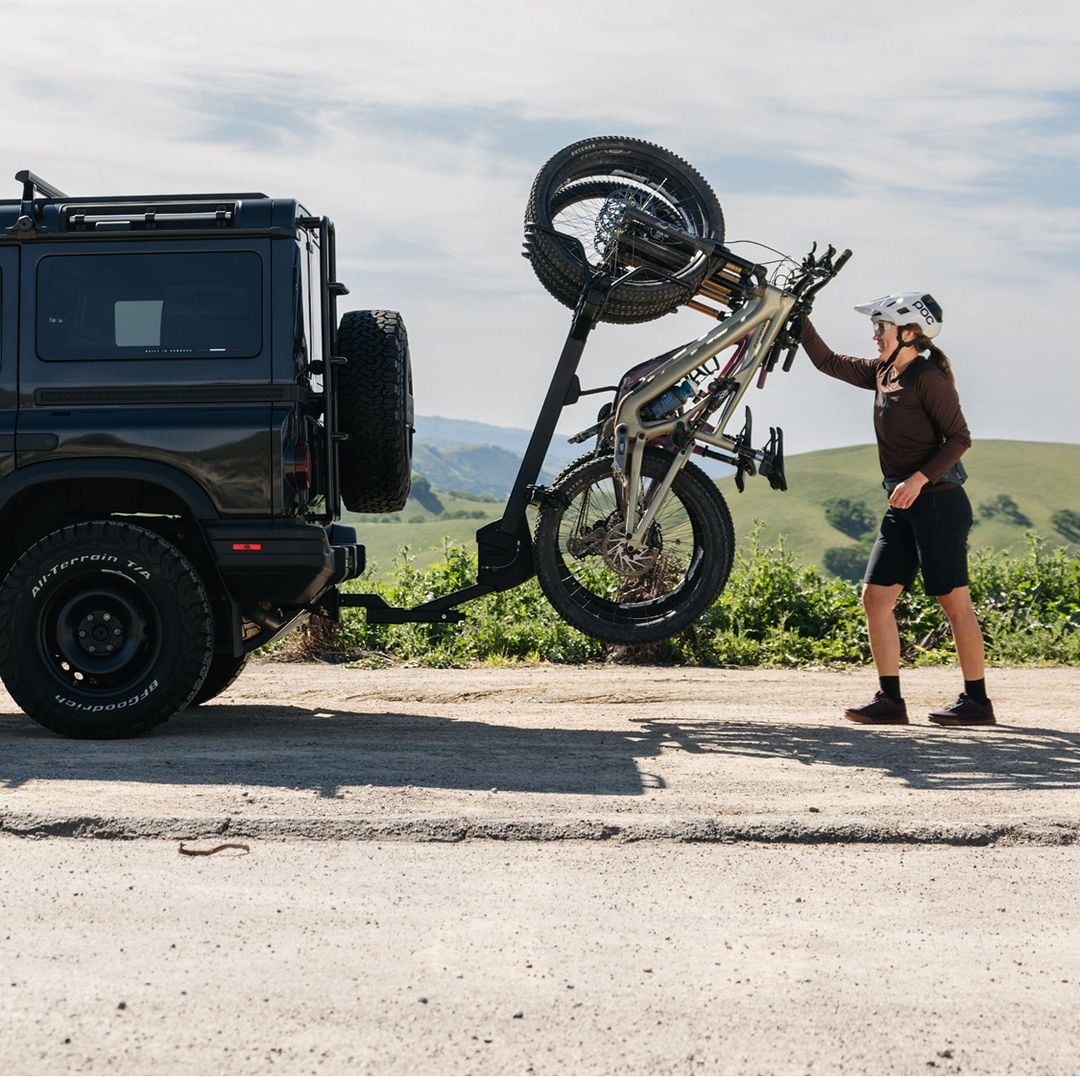Person loading a bike onto a Thule Revert bike rack on the back of an SUV.