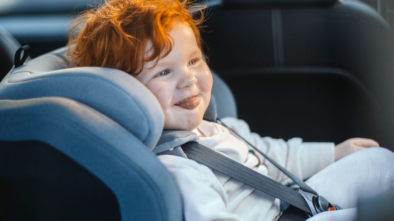 Thule Elm幼児用チャイルドシートに座りながら微笑むオレンジ色の髪の子供。