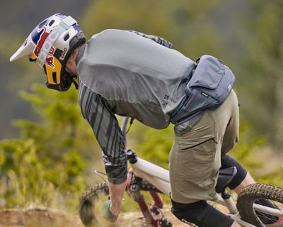 En mountain biker cykler ned ad et spor med en hofteholdt væskebeholder.