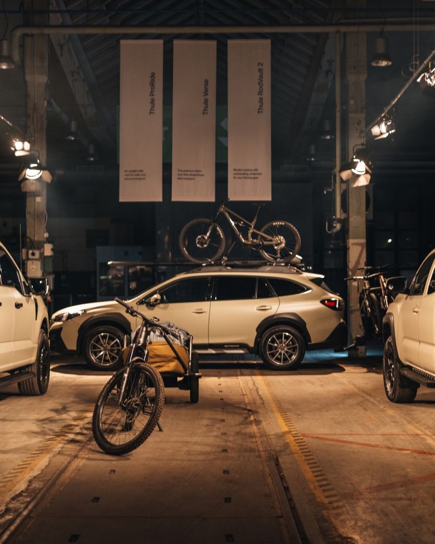 Cars and bikes displayed in an indoor exhibition space.