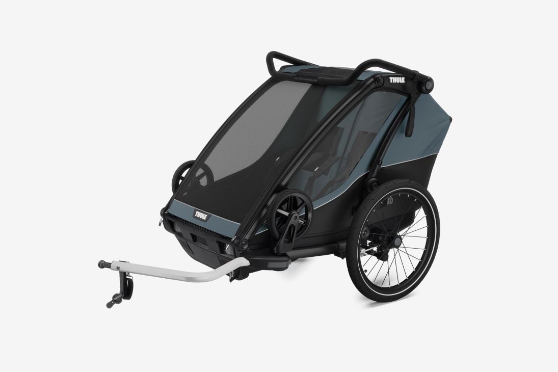 Plava biciklistička prikolica Thule Chariot Cab stoji na svijetlosivoj pozadini. 